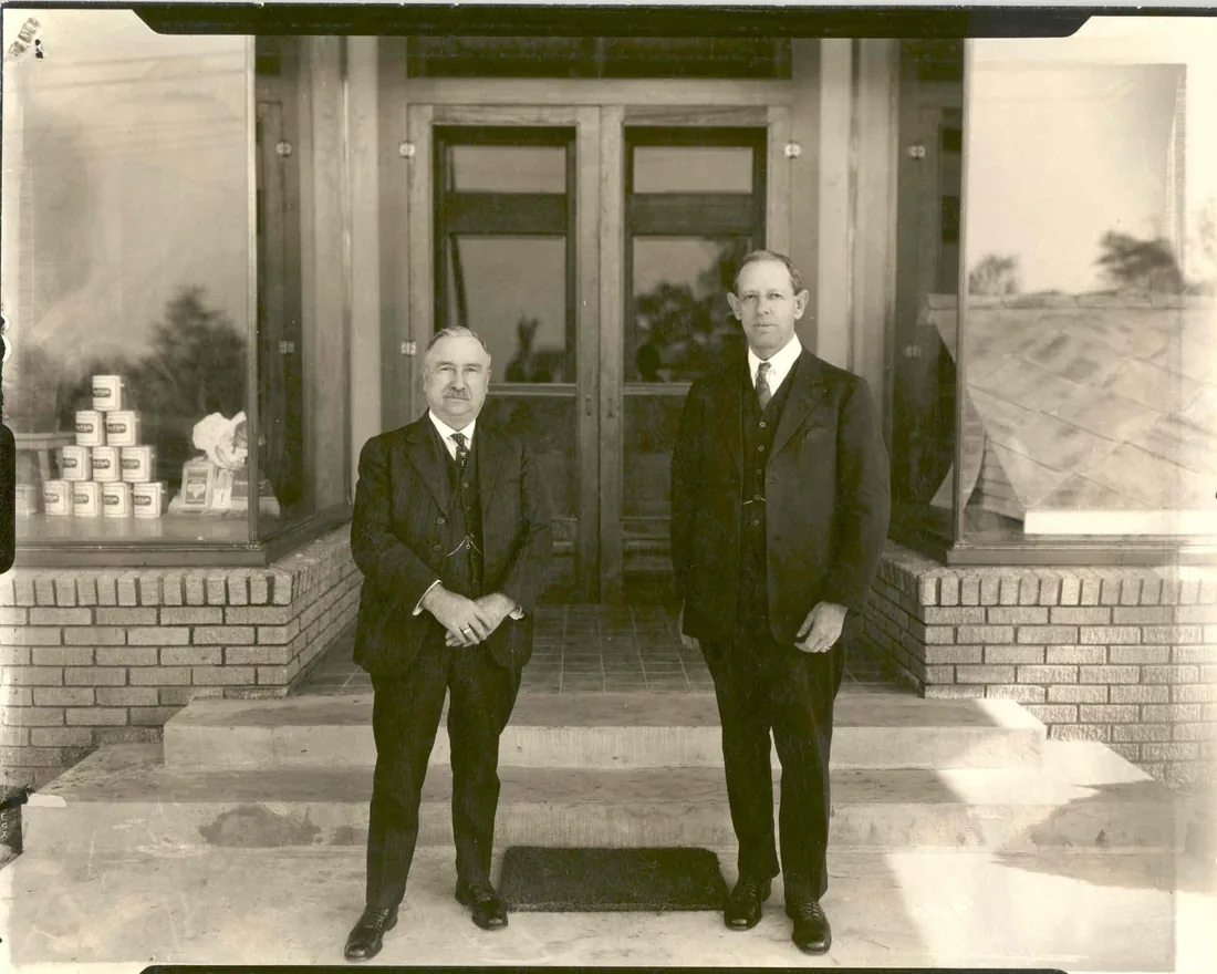 Historic photo of two Krause and Managan founders standing outside a storefront